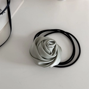 Detail of mint green satin rose hair scrunchie showing elegant petal textures and fabric