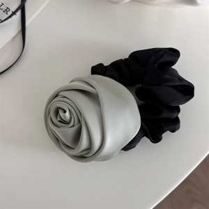 Detail view of a dual-tone hair scrunchie with a grey silk-texture handmade rose bloom