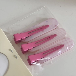 Détail de pinces à cheveux roses à carreaux et pois dans un emballage transparent