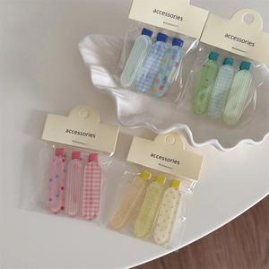 Détail de sets de barrettes colorées à motifs carreaux et fleurs sous emballage OPP
