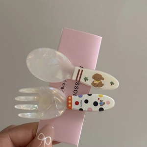 Detail of unique spoon and fork hair clips with puppy patterns and pearl resin finish