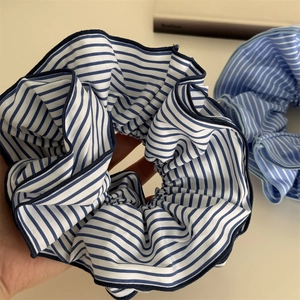 Détail macro de chouchous XL en tissu rayé bleu et blanc avec une texture plissée chic