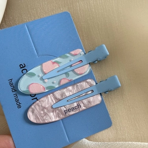 Detail of floral and marble acrylic hair clips with peach motif on a blue display card