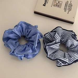 Détail de chouchous en tissu à rayures bleues et blanches sur fond minimaliste épuré
