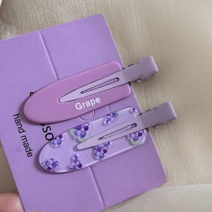 Detailed close-up of two purple floral hair clips with grape designs and handmade cards