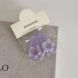 Détail de deux barrettes à fleurs violettes avec motifs blancs sur carte