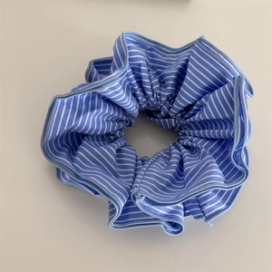 Détail d'un chouchou en tissu à rayures bleues et blanches avec bordure finement cousue