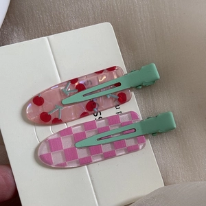 Detail view of sweet floral cherry and checkerboard hair clips on a display card