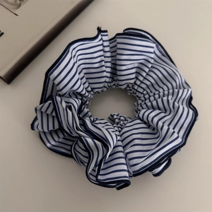 Détail du chouchou en tissu à rayures bleues et blanches avec bords froissés délicats
