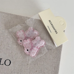 Gros plan de barrettes à cheveux en forme de poisson rose avec motifs floraux sur lin