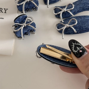 Detail of blue denim texture hair claw and clip with silver metallic bow accents