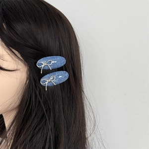 Close-up of blue denim hair clips with silver metal bows on long black hair