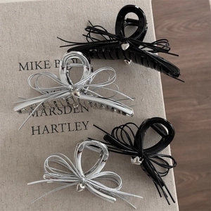 Détails de pinces à cheveux noires et argentées avec pendentifs cœur sur fond gris