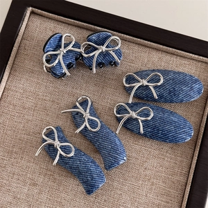 Detail view of 5-piece set blue denim acrylic hair clips with silver bow accents