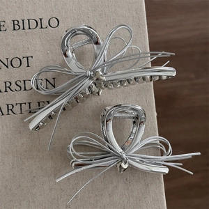 Lot de pinces à cheveux en métal argenté avec nœuds et pendentifs cœur sur un livre