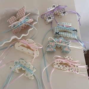 Dettaglio di fermagli per capelli a fiori e quadri con eleganti fiocchi in nastro di raso
