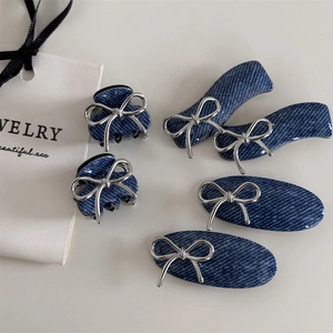 Macro detail of navy denim texture hair clips set featuring silver metal bow accents