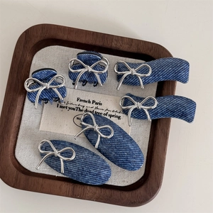 Close-up of 6-piece blue denim hair clip set with silver metal bows in a wood tray