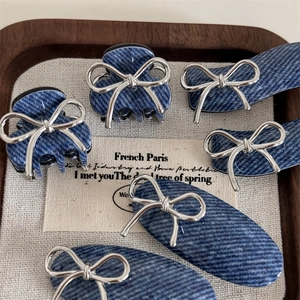 Detail of blue denim fabric hair clips with shiny silver metallic bow ornaments