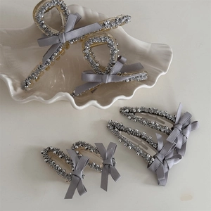 Gray ribbon bow hair clip set with silver beads on a white decorative shell plate