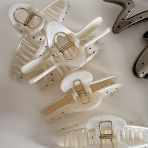 Detail of French polka dot hair claw clip with cream finish and golden metal spring