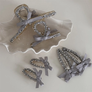 Detail view of grey satin ribbon hair clips with silver bead edges on a shell tray