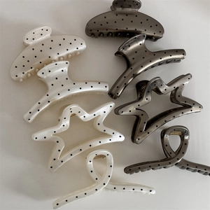 Detail view of large French style polka dot hair claws in cream and smoky grey resin