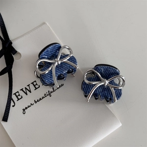 Detail of mini hair clips featuring blue denim fabric and silver metal bow accents