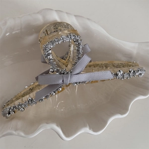 Detail of a large resin hair claw clip with silver beads and a grey fabric bow decoration