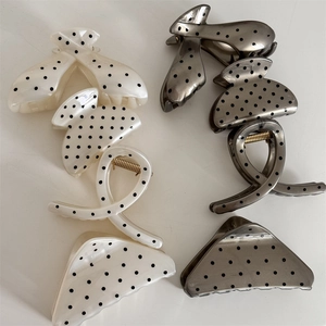 Close-up of elegant French polka dot hair claws in cream and grey with golden springs