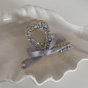 Close-up of a stylish hair claw clip with silver beads and elegant grey ribbon bow