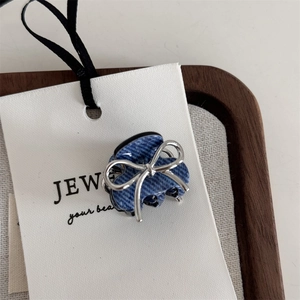 Close-up of blue denim texture hair claw clip featuring a silver metal bow accent