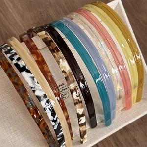 Collection of thin acetate headbands in tortoise shell and marble patterns displayed on stand