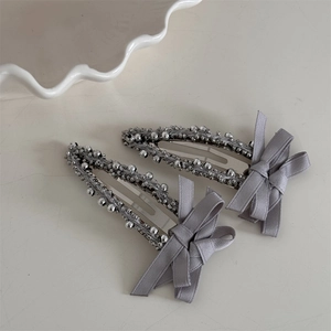 Pair of grey satin bow hair clips featuring intricate silver beadwork on metal drop base