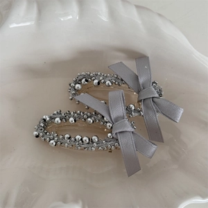 Detail of grey bow hair clips with silver beads set in a white decorative shell tray