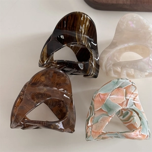 Detail showing four assorted acetate hair claws with marble and pearlescent textures
