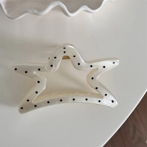 Detailed top view of cream star hair claw clip with black polka dots and gold spring