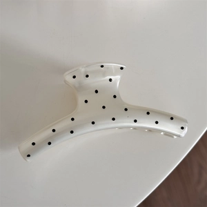 Macro view of cream large hair claw clip with black polka dots and smooth resin finish