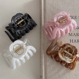 Detail view of large marble and solid color resin hair claws with gold springs