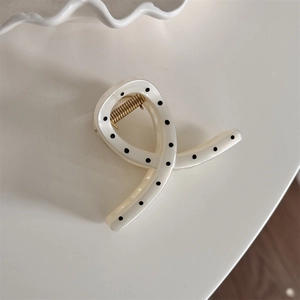 Detail of elegant cream hair claw clip with black polka dots and golden metal spring