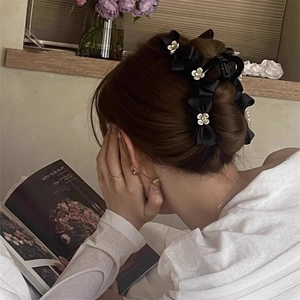 Elegant black bow hair claw with pearl flowers shown on a woman styling her hair
