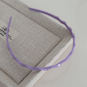 Détail d'un serre-tête ondulé violet sur une boîte beige avec une finition brillante