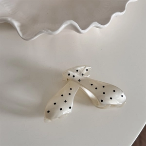 Detailed view of a cream claw clip with black polka dots and a glossy acetate finish