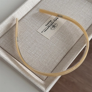Close-up of cream acetate headband with non-slip inner teeth on a textured tray