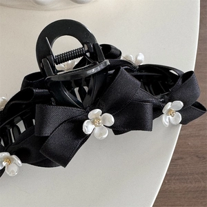 Detailed macro view of black ribbon bow hair claw clip with white floral decorations