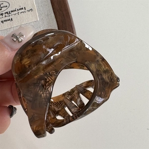 Detailed close-up of amber tortoiseshell claw clip made of polished acetate resin