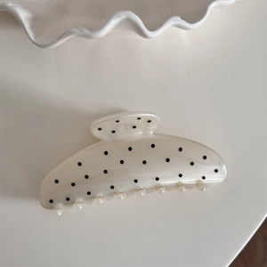 Close-up of cream claw clip with black polka dots and transparent comb teeth
