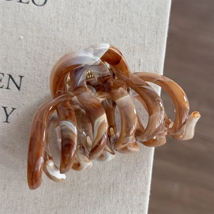 Detail view of the large amber tortoiseshell hair claw with golden spring mechanism