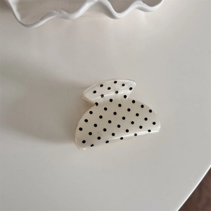Detail view of a French vintage cream hair claw clip with classic black polka dots pattern