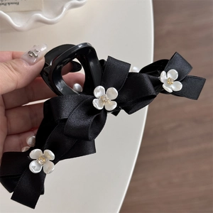 Elegant black satin bow hair claw clip with delicate white flowers and golden accents